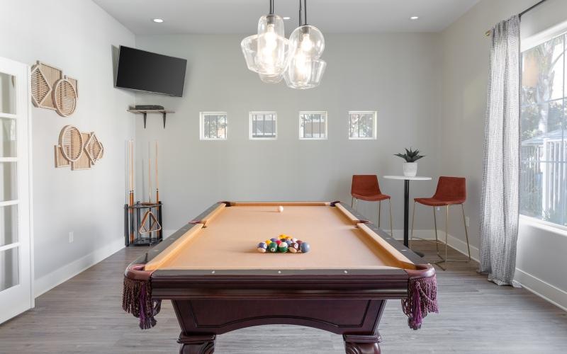 a room with a pool table and chairs