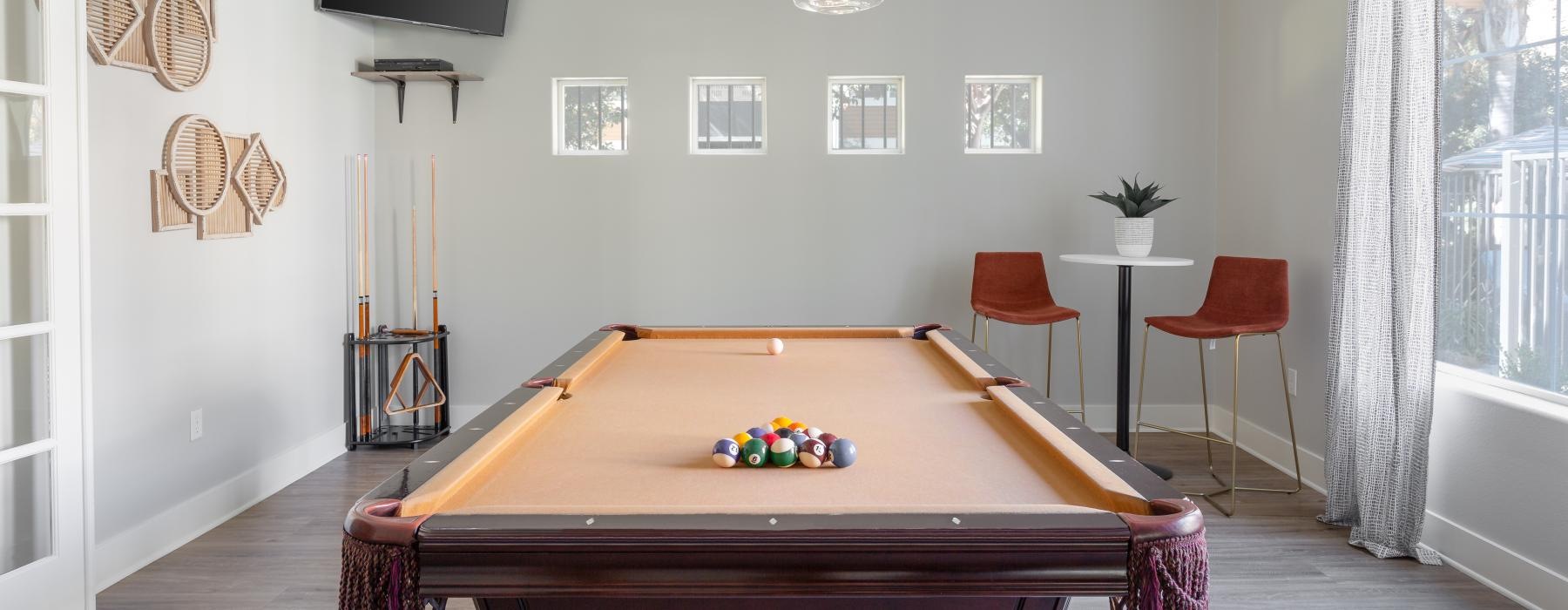 a room with a pool table and chairs