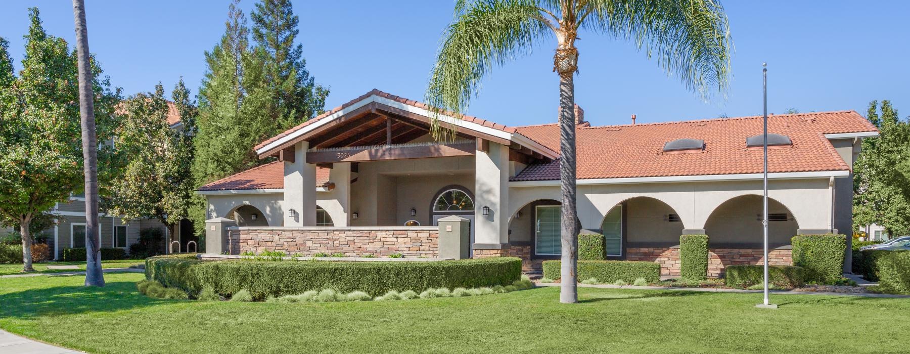 clubhouse with a palm tree and a lawn in front of it